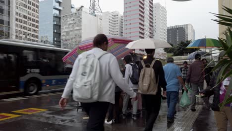 crowds move through a lively urban area during a downpour, where vendors serve delicious street food while pedestrians stay dry under colorful umbrellas