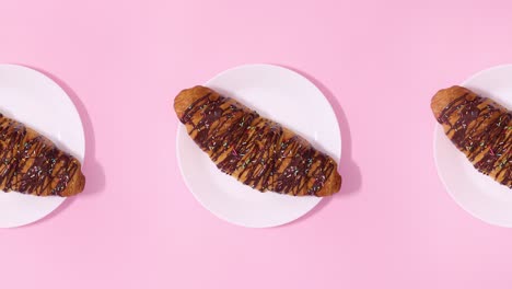 three fresh delicious croissants rotate on pink theme. stop motion