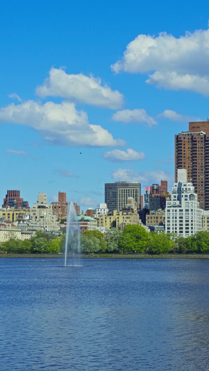 Fonte do Reservatório Onassis e horizonte de Manhattan no Central Park sob um céu azul de verão, cenário vertical de médio plano, estático.