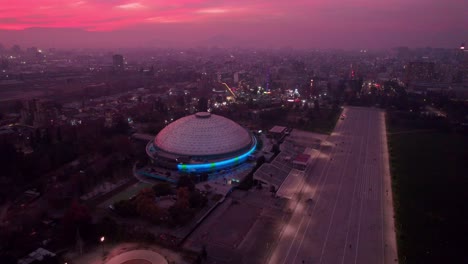 focus on movistar arena stadium under pink sunset sky in middle of urban downtown of santiago, chile