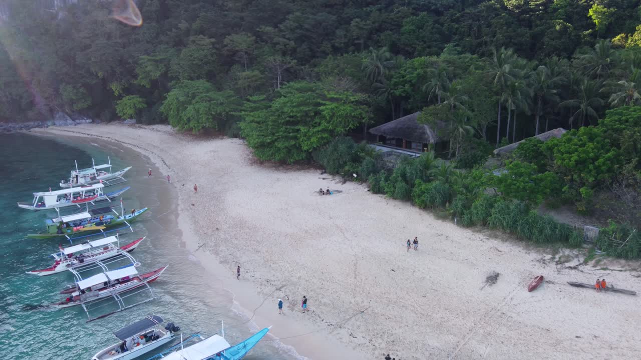공중 전망 : 헬리 ⁇ 터 섬, 엘 니도 의 열대 해변 오두막 을 배경 으로 하 ⁇  모래 해변 을 따라 투르코이즈 색 의  ⁇ 은 물 에 정박 한 다수의 다채로운 필리핀  ⁇ 카 투어 보트