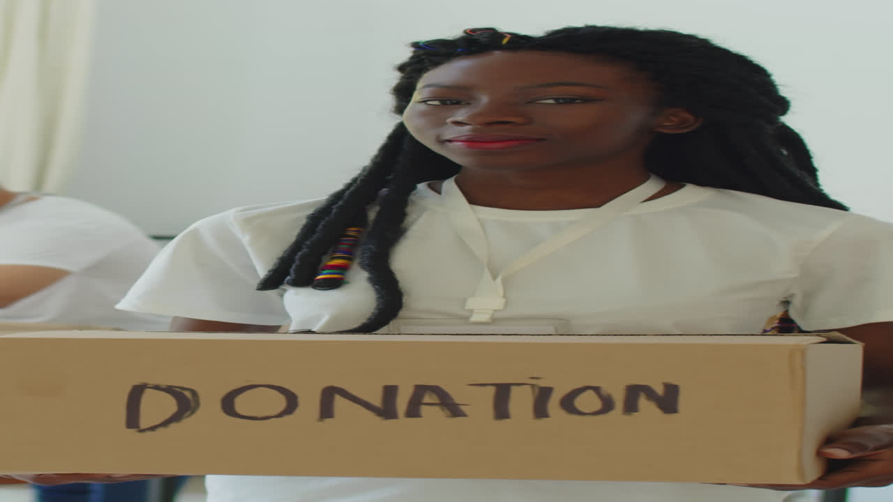 Smiling Black Woman with Donation Box in Volunteers Center