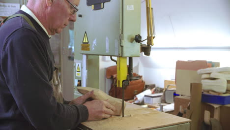 bespoke shoemaker shaping wooden last for shoe using jigsaw