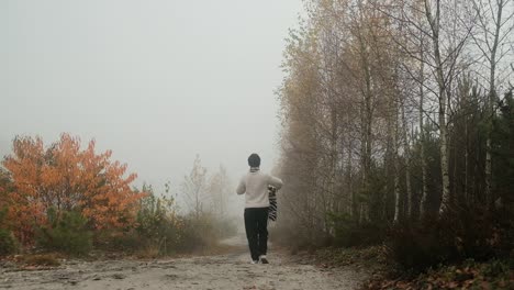 女人在雾天在秋天的森林里走路