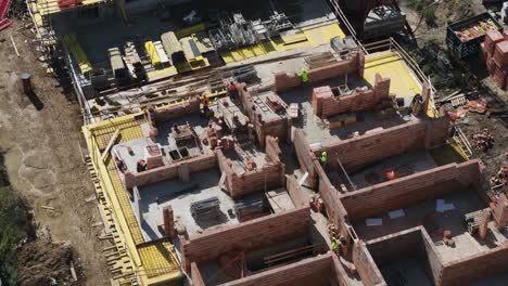 aerial view of construction site: workers building brick walls of new residential houses