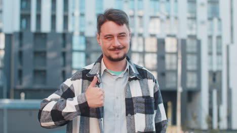 happy mature caucasian man showing thumb up gives positive reply standing on downtown city street