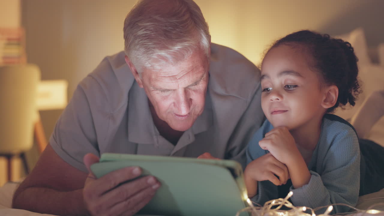 Grandfather, child and tablet on bed