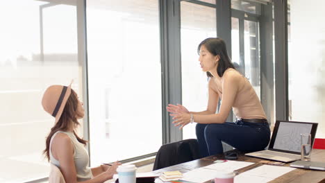 discussing design ideas, multiracial women collaborating in modern office with coffee and documents