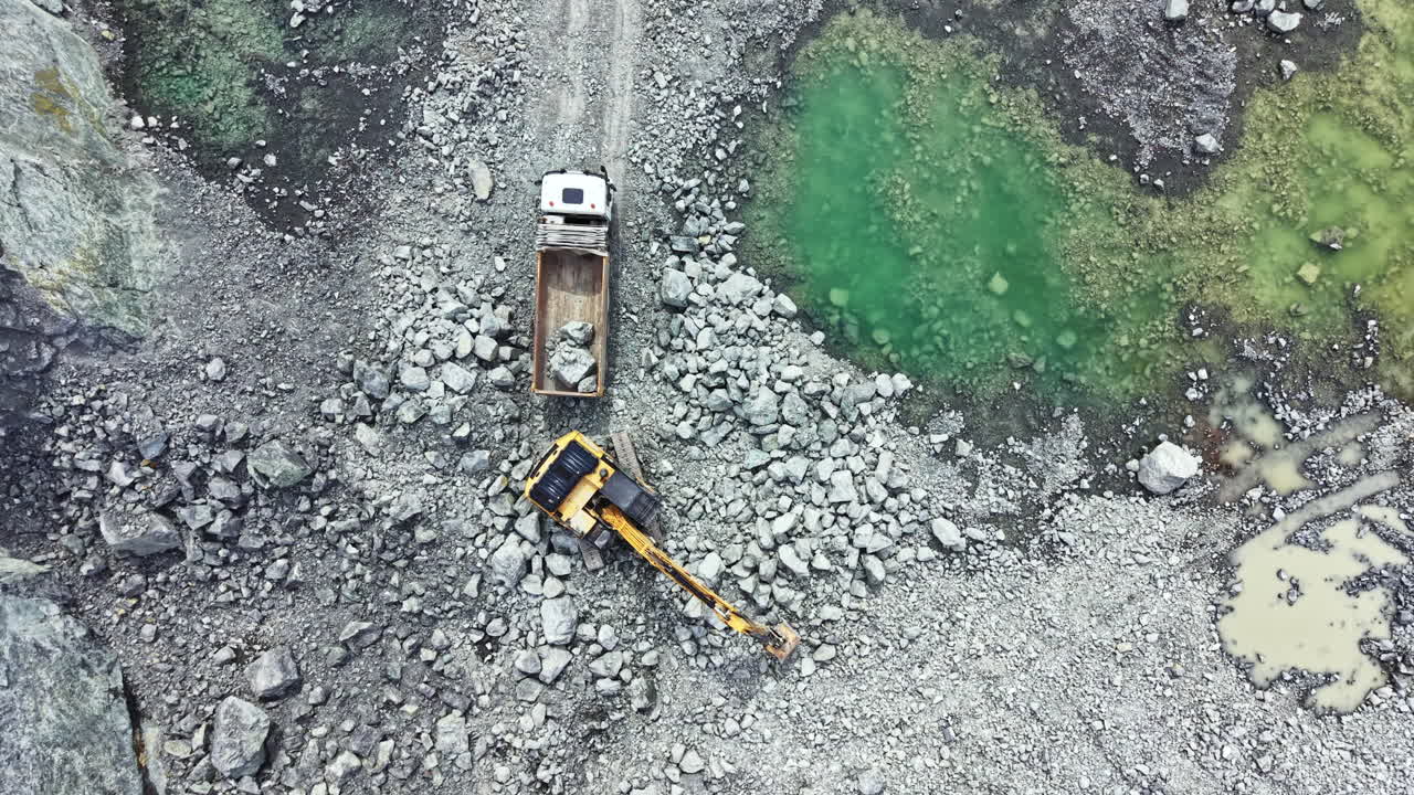 Heavy equipment works at granite quarry site in remote location during daytime to extract rock materials for construction projects