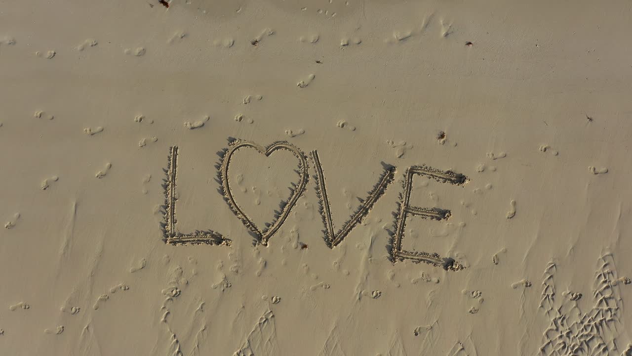 해변의 모래에 새겨진 사랑의 공중 미친 터닝 샷