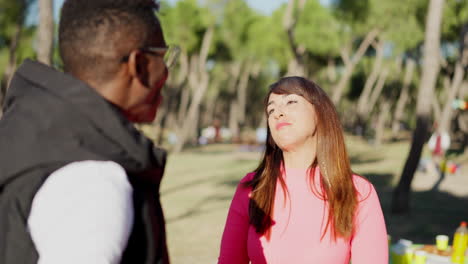 two friends having a casual conversation at an outdoor gathering in a park