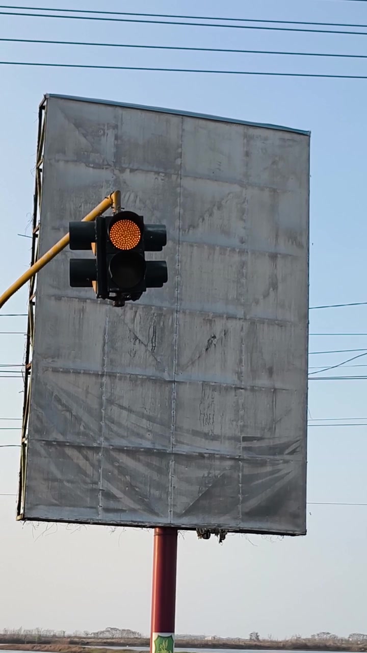 Blinkende gult trafiklys foran tomt reklameskilt