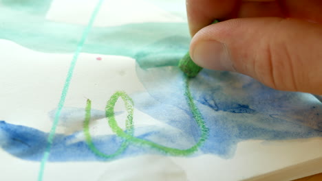 niño garabateando con pastel de cera en papel de arte desordenado