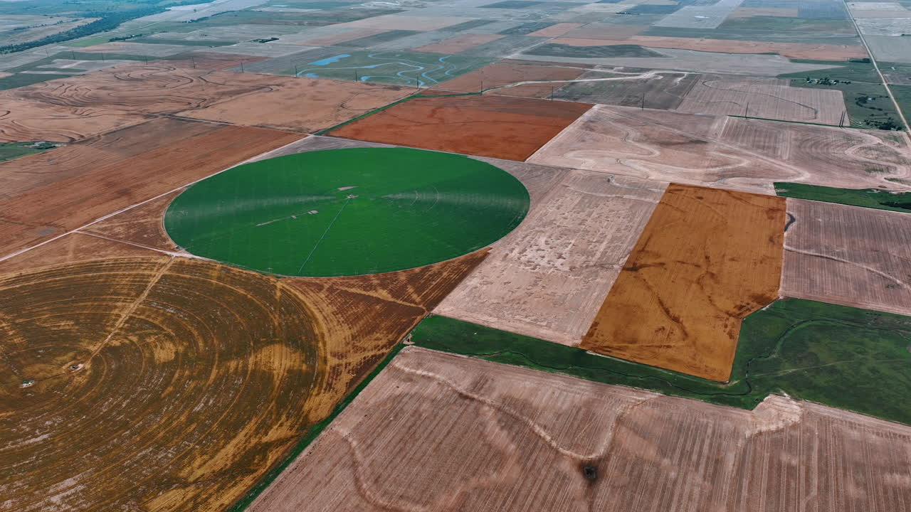 View on two circular farms with green plants on and without. Bare rectangular fields and green fields around top perspective.