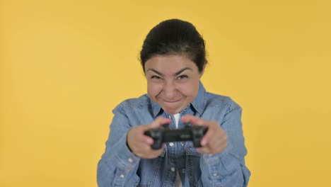 young indian woman playing video game, yellow background