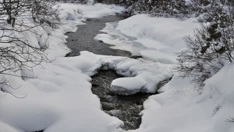 Lapso-De-Tiempo-De-Un-Pequeño-Arroyo-En-Los-Alpes-Franceses-Que-Tiene-Lados-Y-Bancos-Cubiertos-De-Nieve