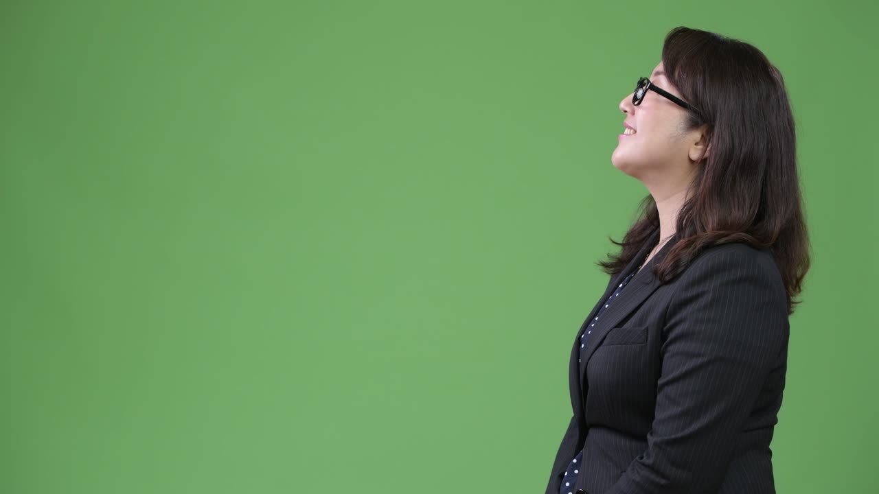 Vista di profilo di matura e felice donna d'affari asiatica su sfondo verde.