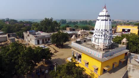 Aerial-pedestal-up-and-panning-of-colorful-Hindu-temple-of-rural-Indian-village-of-Khera-Kiran-in-Rajasthan,-India