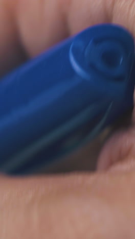 hand of mature man holds new ball pen in transparent case on dark background extreme close view