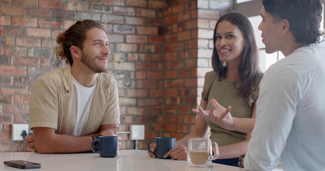 Friends at bar in cafe over coffee, right man starting talk, gesturing, woman holding mug, phone