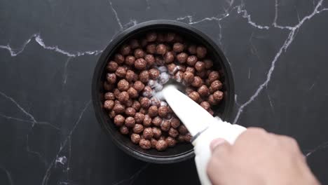 pouring milk over chocolate cereal