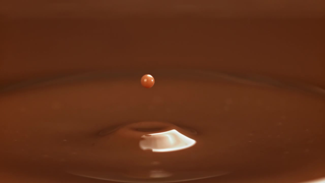 Uma única gota de chocolate criando um respingo em coroa e ondulações em câmera lenta