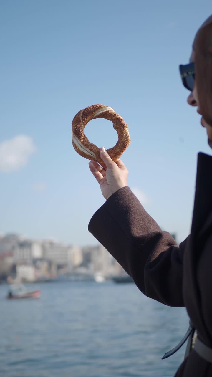 Woman Holding Traditional Turkish Simit with Scenic Istanbul View