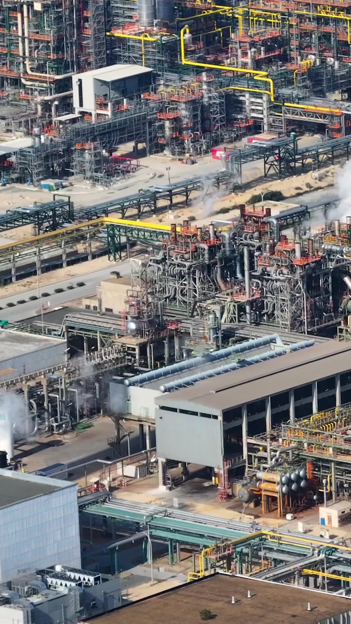 The video shows operations at an oil refinery complex in an industrial area. Activity includes processing of petroleum and various energy infrastructure components.