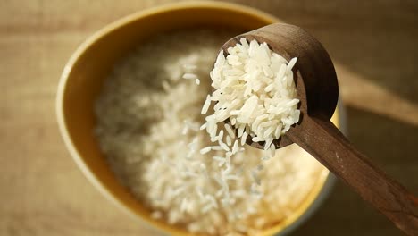 white rice in a bowl with wooden spoon