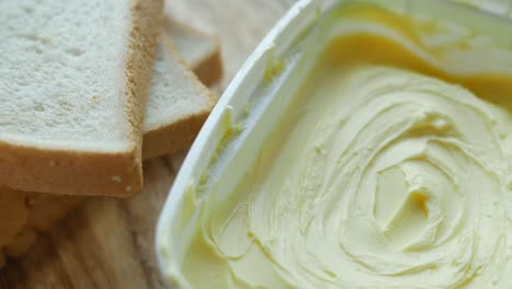 Fresh-butter-in-a-container-with-bread-on-white-background