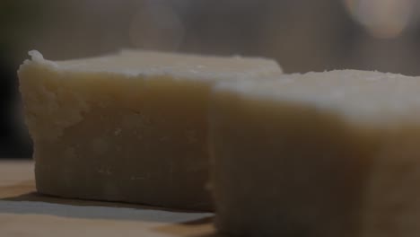 Parmesan-cheese-fresh-pieces-rotating-on-wooden-table,-closeup---Portugal