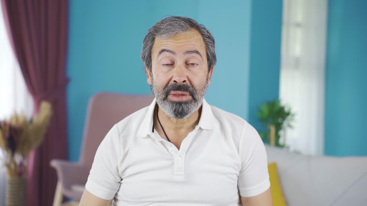 Cute old man yawning. He is looking at the camera.