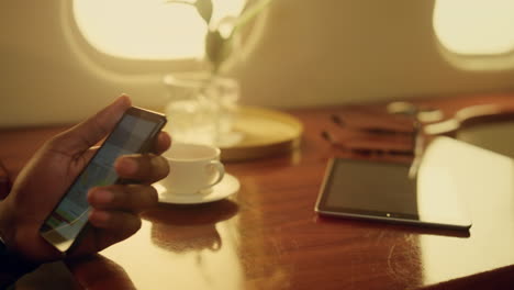 businessman using cell phone on flight. closeup hands hold smartphone in plane