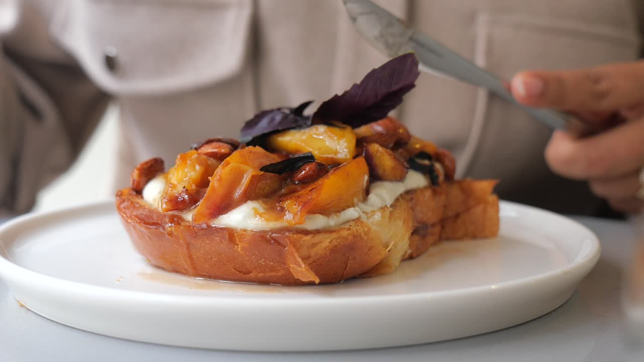 Persona che mangia French toast gourmet con pesche e panna