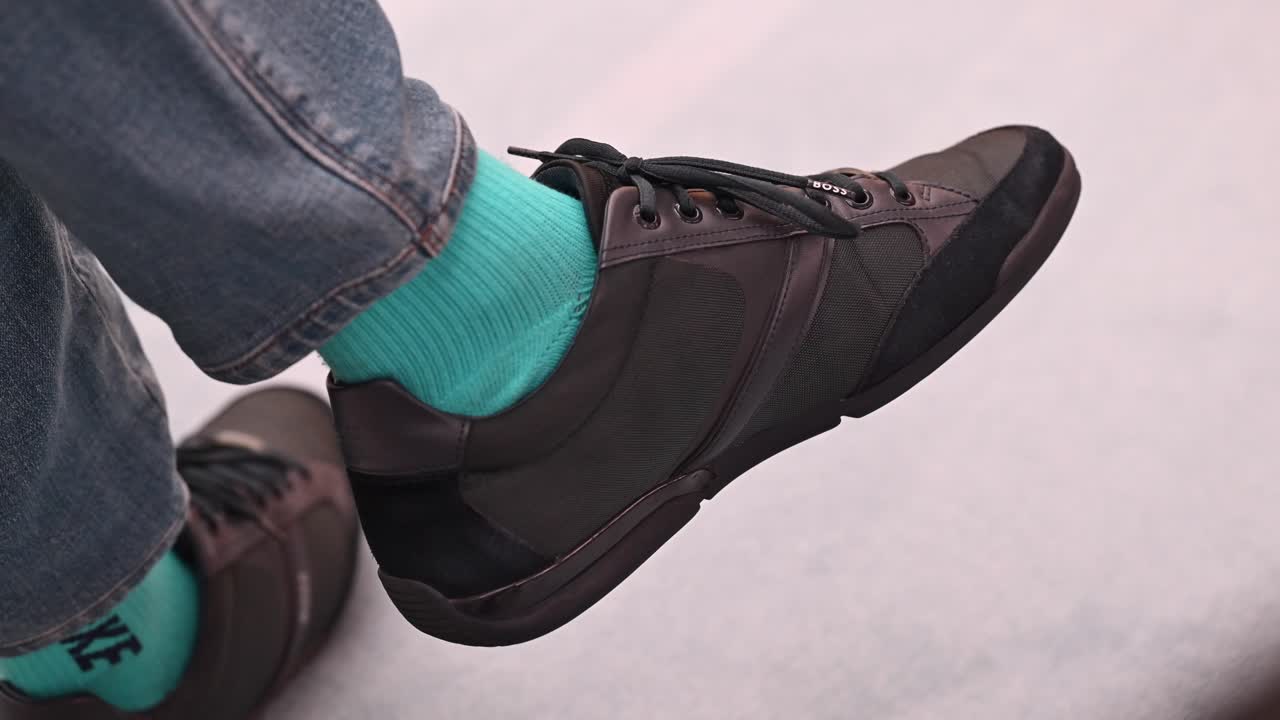 un hombre con zapatillas de deporte con calcetines verdes se sienta en la silla