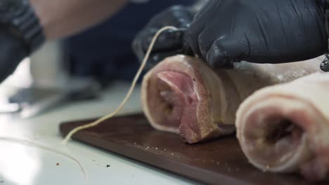 master chef using thread to prepare delicious meat roll in kitchen