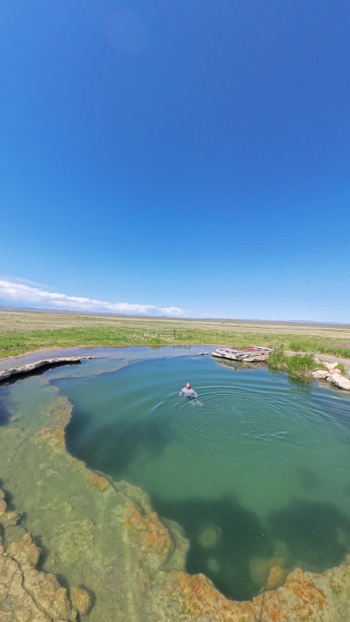 Vertical video of a Hot Spring in Utah with a red haired male jumping into the water and swimming