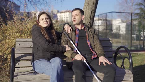 la esposa ama a su ciego esposo. están sentados en el parque.