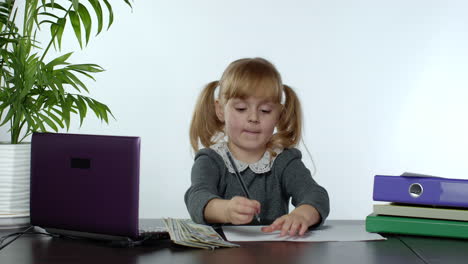 child girl boss counting dollar cash bills. baby businesswoman kid with money is sitting at office