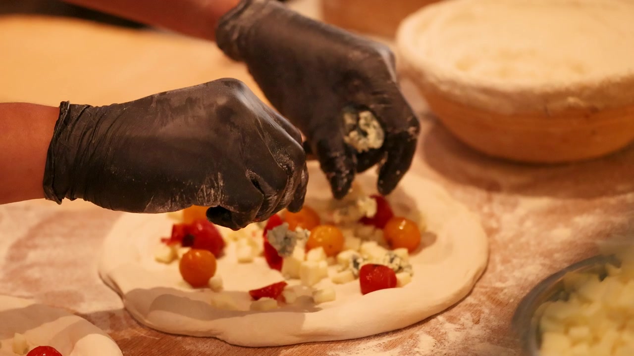 Chef che prepara una pizza gourmet con ingredienti freschi in cucina