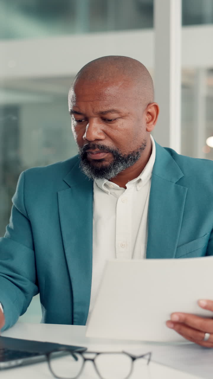 Focused Businessman Working on Laptop and Reviewing Documents in Office