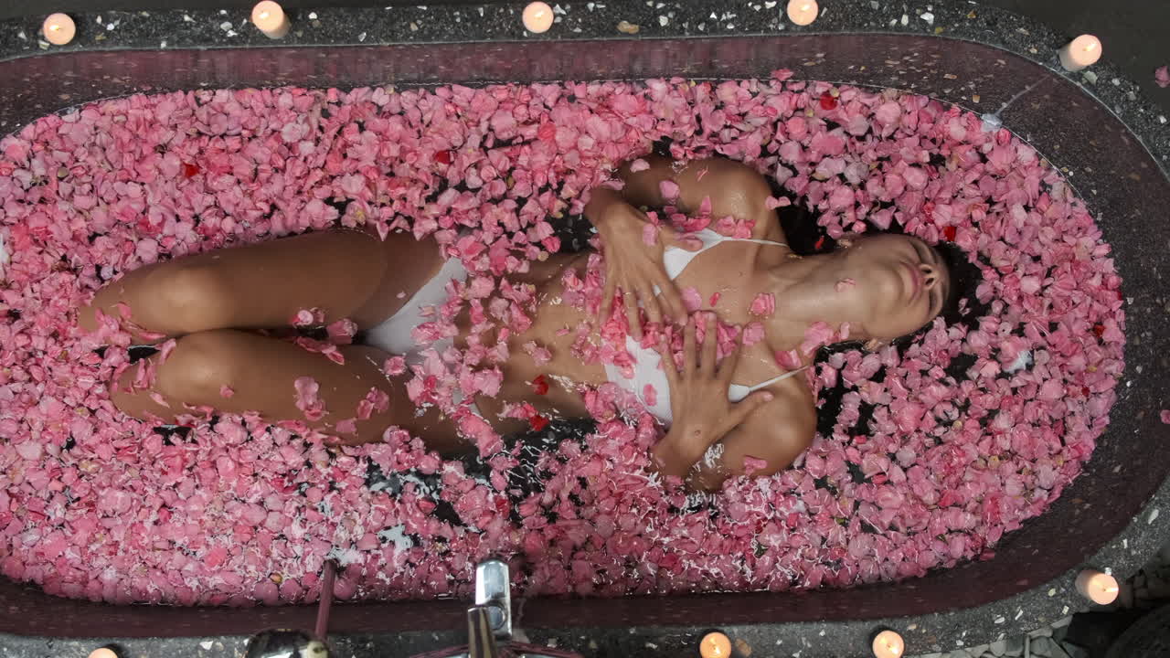 женщина наслаждается расслабляющей ванной с розовыми лепестками