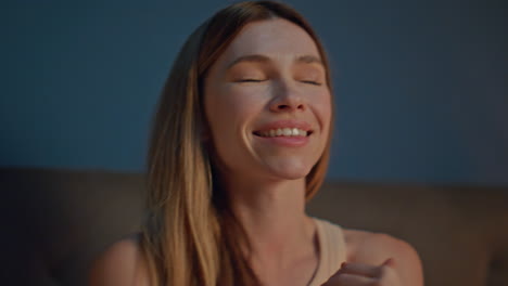 relaxed woman moisturizing hands with nourishing cream in evening bed close up.