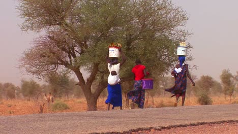 women walk carrying goods on their heads through the sahara desert in mali 3