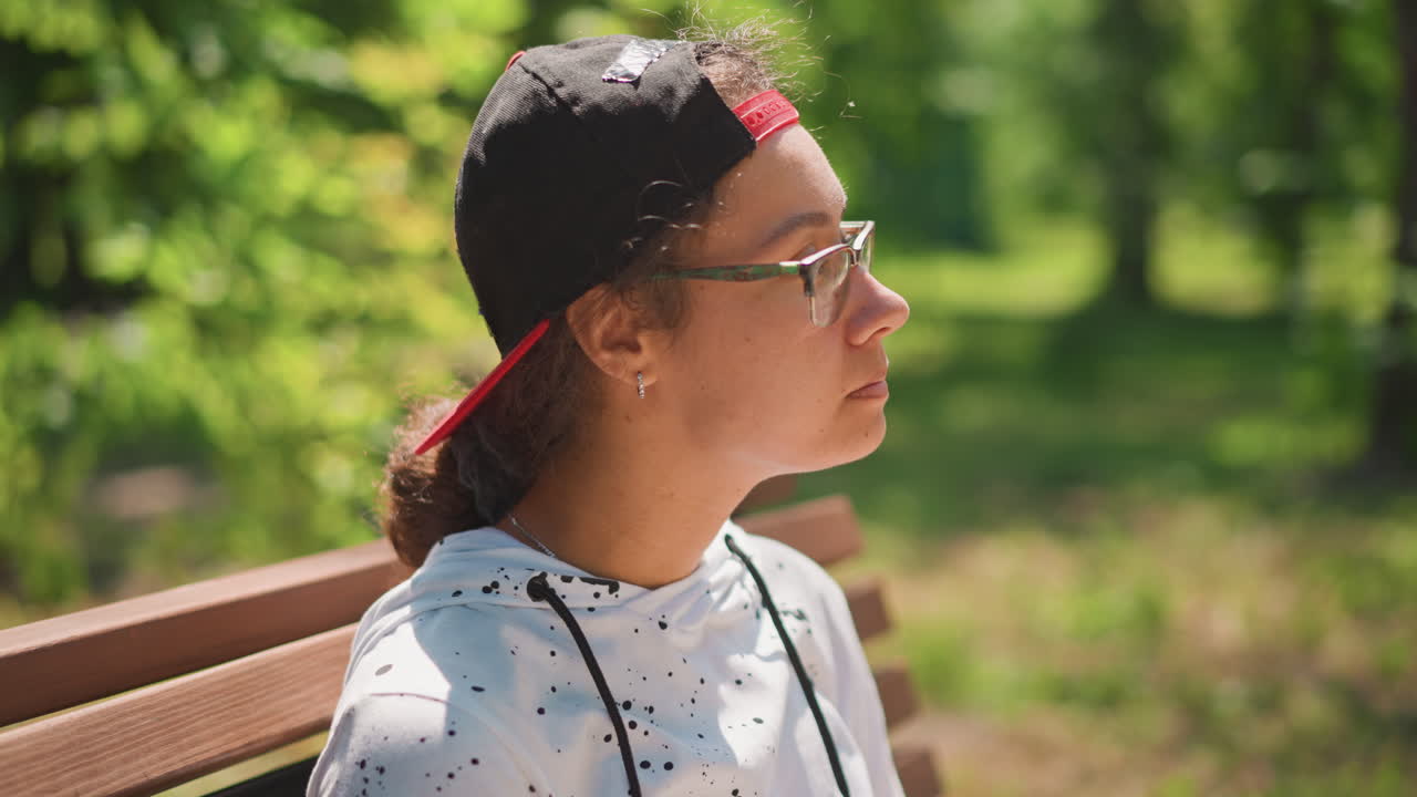 공원에서 점심을 먹고 있는 벤치에 앉은 여성의 넓은 구도, 휴식을 취하는 학생, 관찰하기 위해 멈춰 선 작가, 햇빛을 들이쉬는 자연을 사랑하는 사람, 옆에 있는 백팩, 그릇과 용기, 뒤로 돌린 모자, 평온한 위쪽