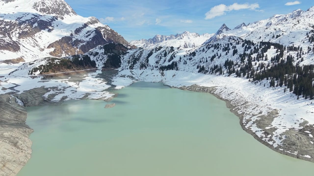 Sorvolo Aereo di un Lago di un Bacino Idroelettrico in Montagna Alpina Innevata.