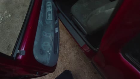 pov shot of a person opening a red car door and sitting down on the seat