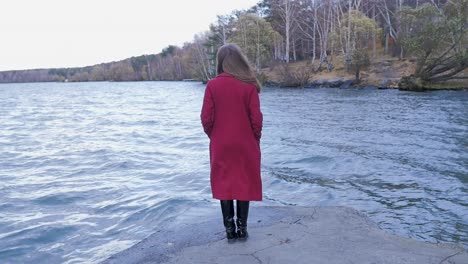 woman in red coat by the lake