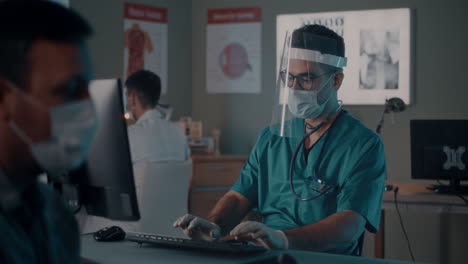 doctor consults with patient using a computer in a medical office during covid-19 pandemic