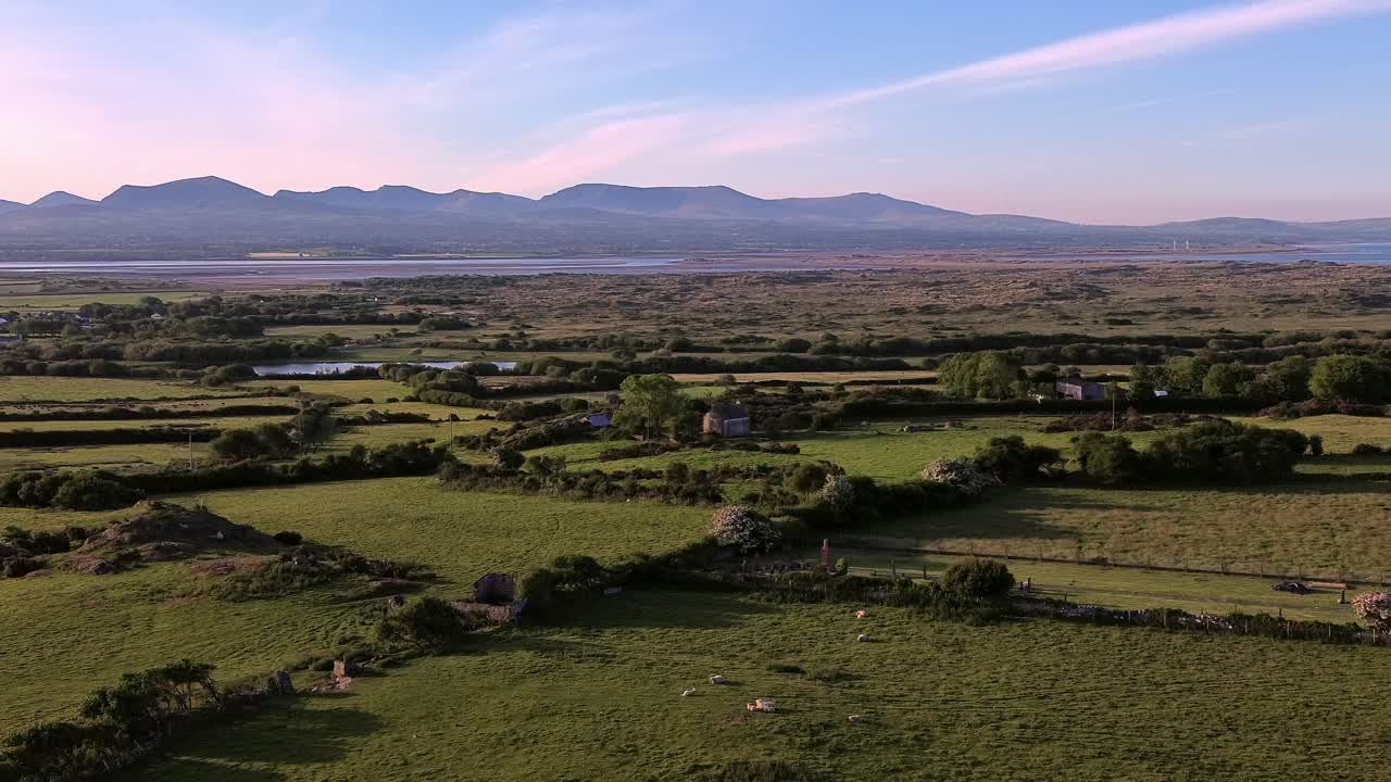 Idyllic Welsh meadow under Snowdonia mountains aerial panning view across rural Eryri national park